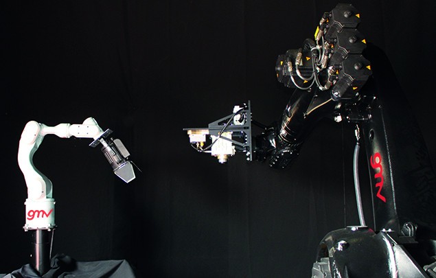 Two robot arms facing each other in GMV’s darkened platform-art hall during EROSS+ testing