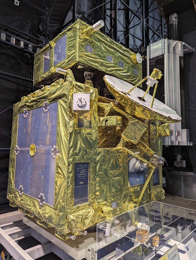 Two gold foil-wrapped boxes stacked, blue solar panels on their faces and a white dish
