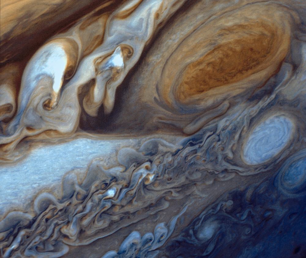 Close view of swirling cream and brown cloud bands around a large orange oval