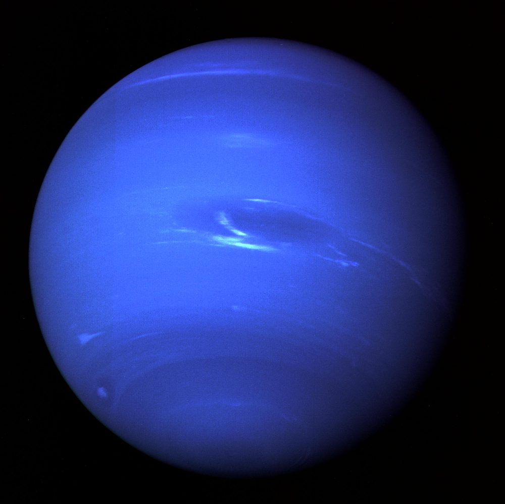 Deep blue globe with a dark oval and bright white cloud streaks beside it