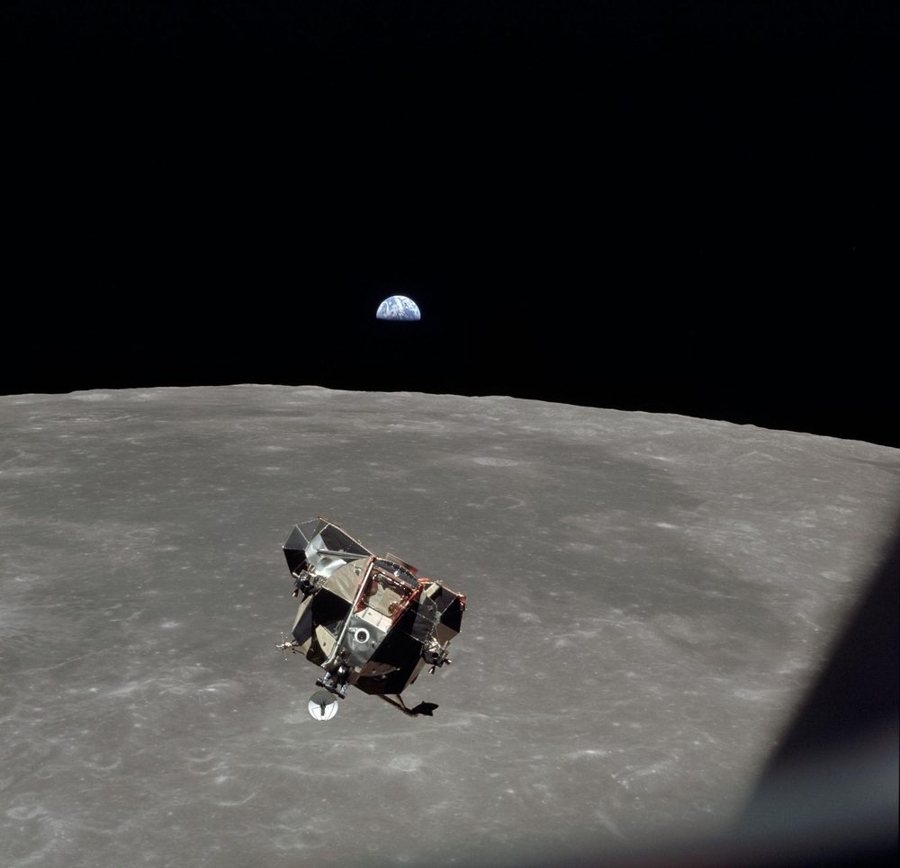 Angular ascent stage above the grey cratered surface, half-lit Earth on the horizon
