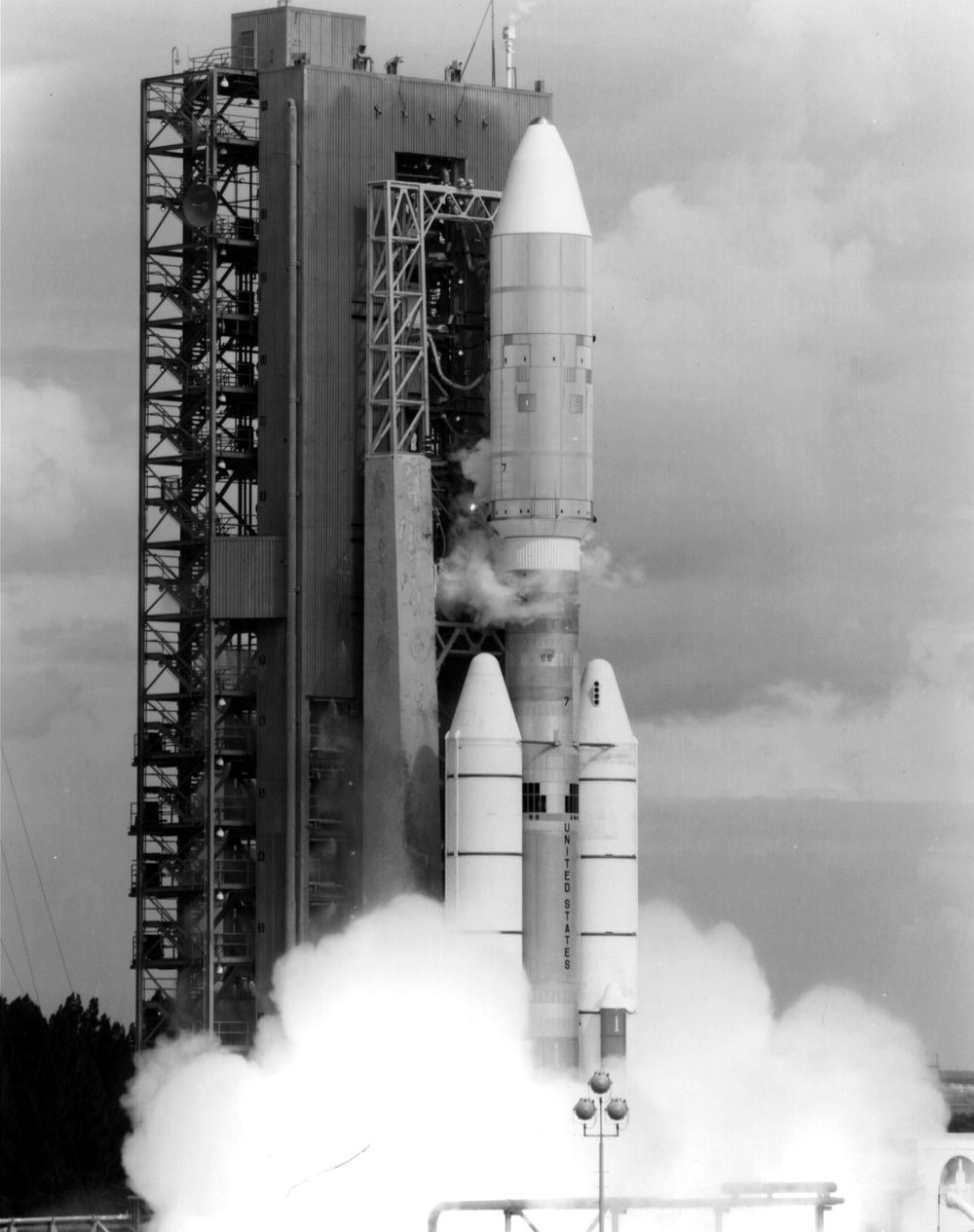 Rocket clearing its service tower in dense exhaust, in black and white