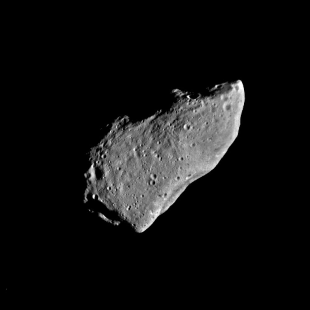 Elongated grey wedge of rock, pitted with small craters, lit against black
