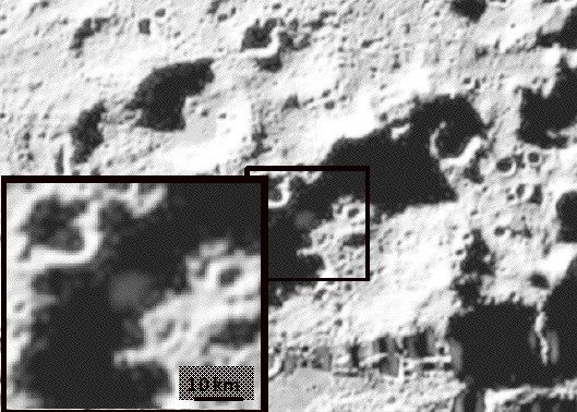 Coarse monochrome frame of shadowed cratered ground, with a boxed area enlarged as an inset