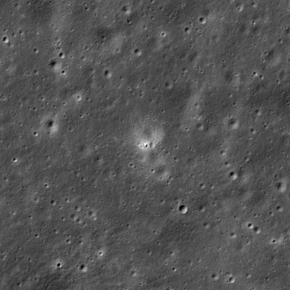 Grey cratered surface with a single bright point at centre inside a pale halo