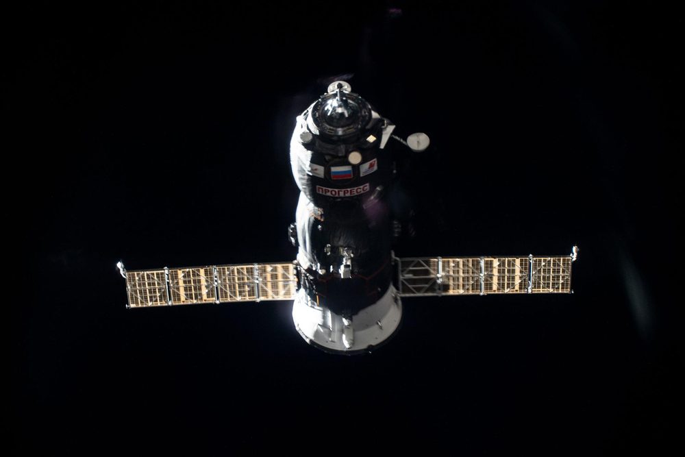 Freighter head-on in darkness, gold solar wings spread wide, Cyrillic lettering on the hull